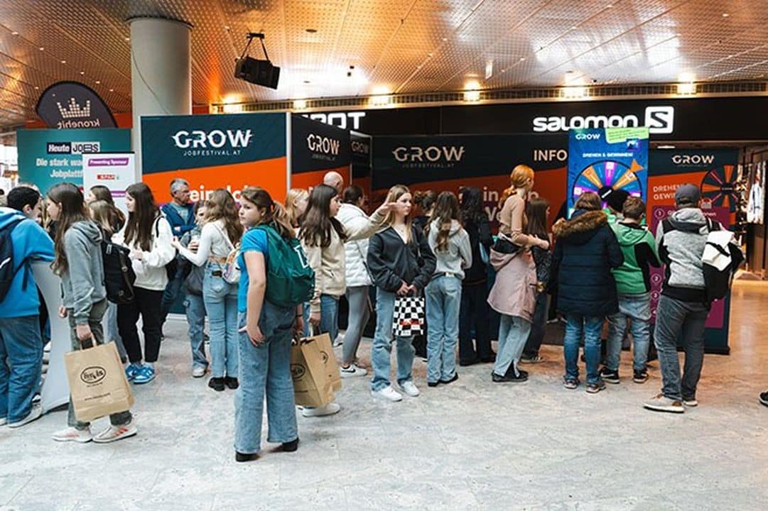 Meinkarrierestart.at Eine Gruppe von Menschen, hauptsächlich Teenager, steht in einem Einkaufszentrum an einem Indoor-Veranstaltungsstand mit der Aufschrift „GROW“ Schlange.